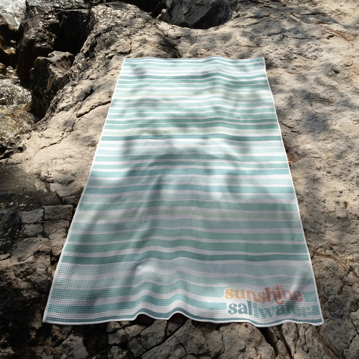 Sea Glass striped beach towel in blues and greens, lightweight microfiber, quick-dry, and sand-free.