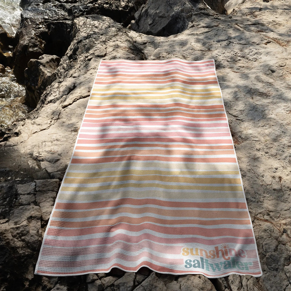 coral orange beach towel laying on beach