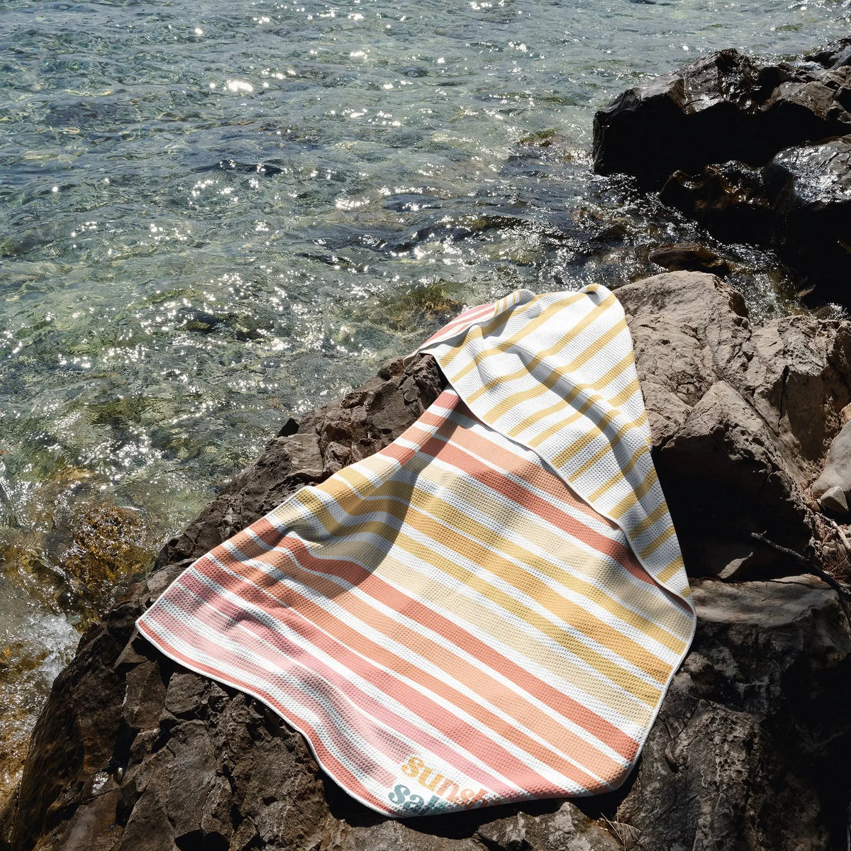 sunshine and saltwater oversized waffle beach towel folded over on a cliff overlooking the beach